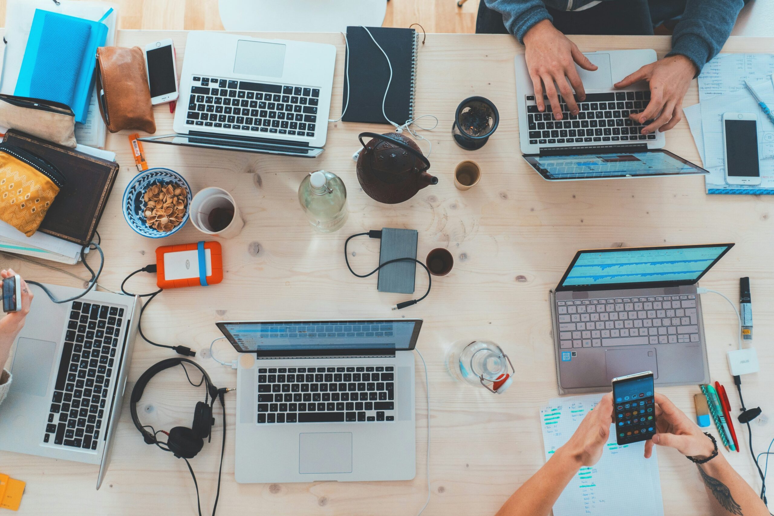 a group of people sitting at a table with laptops and cell phones